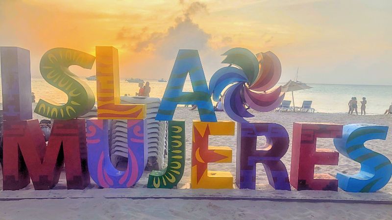 Señal colorida en la playa que dice "Isla Mujeres"