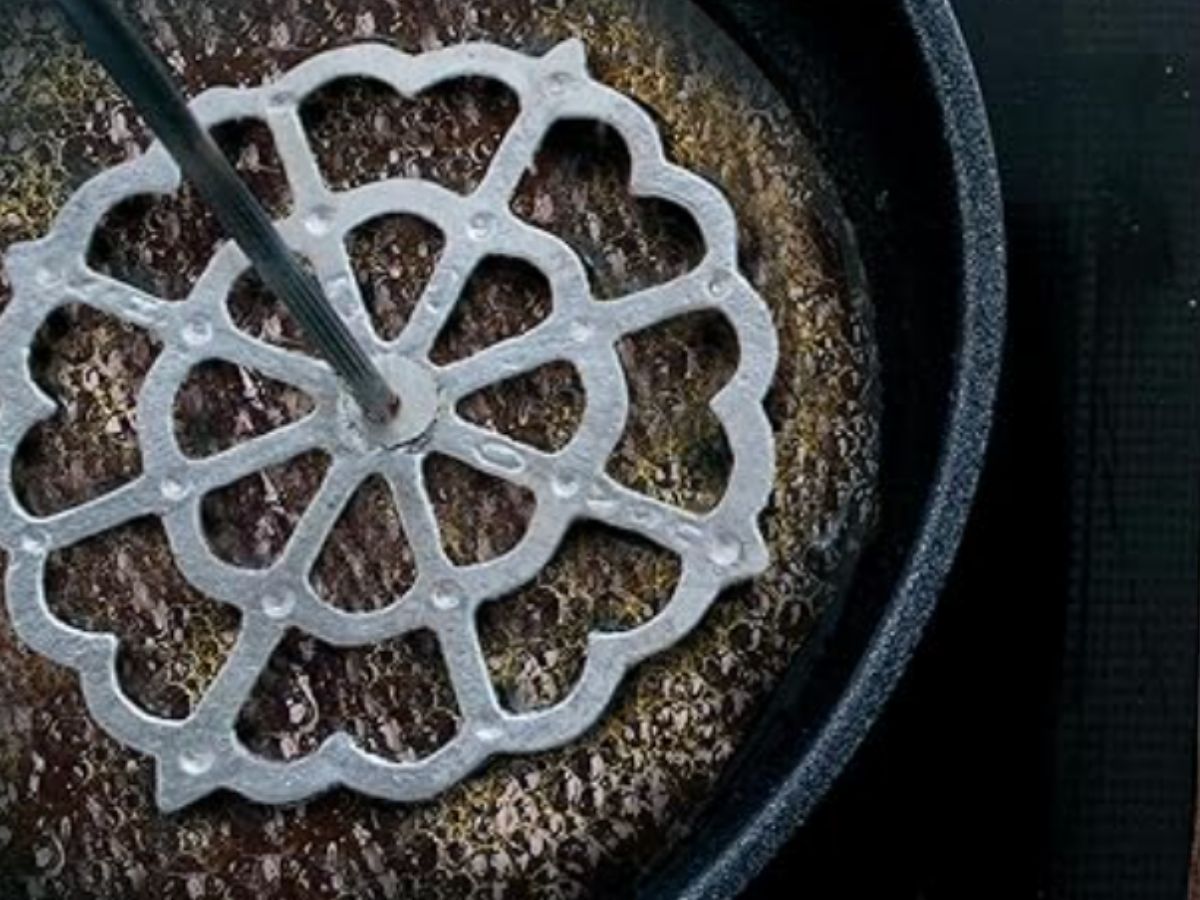 mojar la roseta de hierro buñuelera en aceite caliente