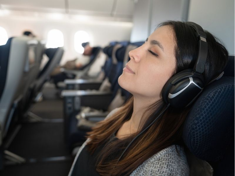 mujer durmiendo en el avión con los auriculares puestos