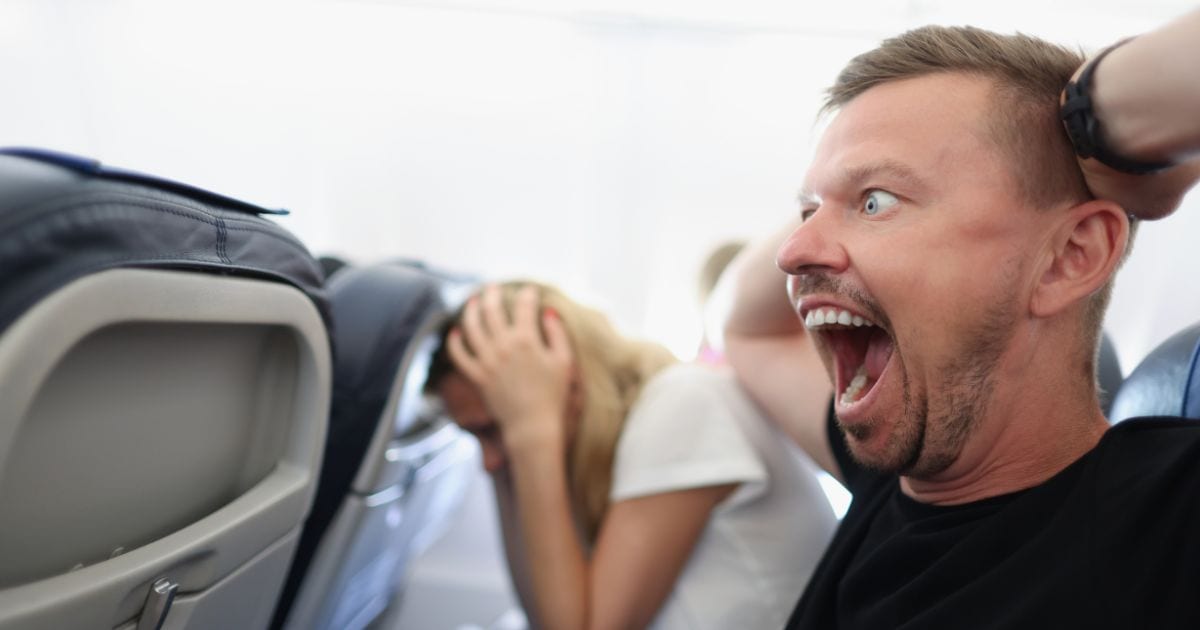 man scared and angry on a plane because he's not sitting in one of the best seats on a plane