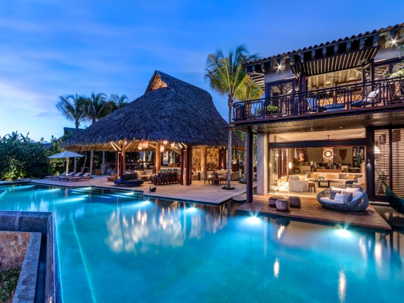 Piscina infinita y palapa iluminadas al atardecer en Casa Koko, una villa frente al mar en Punta Mita