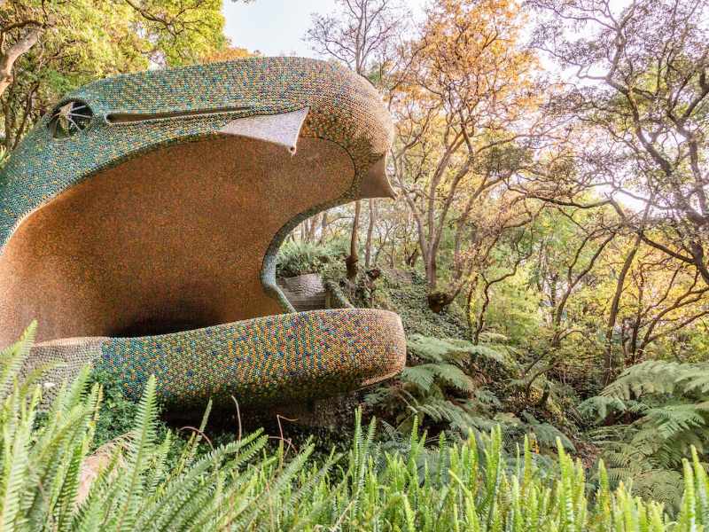 La cabeza de serpiente con la boca abierta de El Nido de Quetzalcóatl entre los árboles
