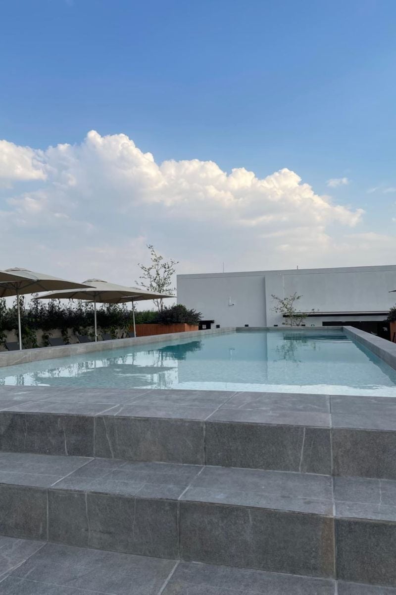 Piscina en la azotea del edificio bajo un cielo azul en Roma Suite with a Building Pool, un Airbnb económico en la Roma Norte de la Ciudad de México