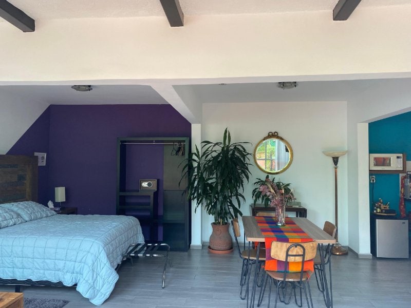 Dormitorio y comedor con paredes de color púrpura en la Casa de la Sierra Loft con terraza en Guadalupe Inn, Ciudad de México