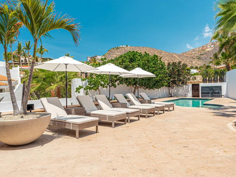 Terraza de la piscina con tumbonas y sombrillas en la Villa Pedregal de 4 dormitorios a pasos de la playa en Cabo San Lucas