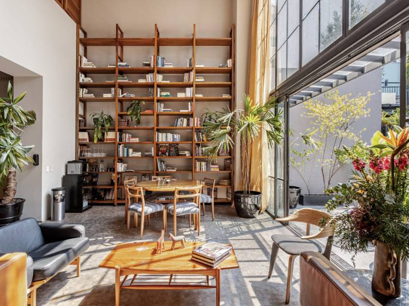 Sala de estar de doble altura con estanterías de piso a techo en Serviced 4-Bedroom Designer Mansion, un Airbnb de lujo en la Condesa de Ciudad de México