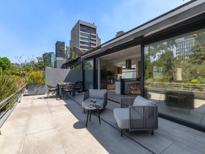 Soleada terraza privada con reposeras con vista a los árboles en el Apartamento Capitalia en Polanco, Ciudad de México