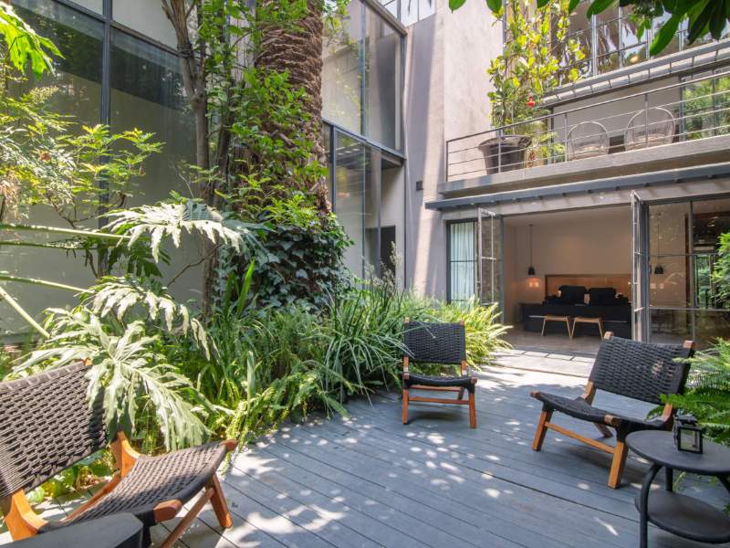 Patio central lleno de plantas con sillones en la mansión de diseño de 4 dormitorios con servicios en Condesa, Ciudad de México