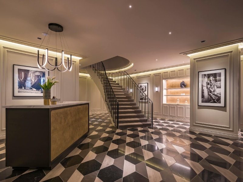 Elegante vestíbulo con piso de mármol a cuadros y escalera curva en The Amsterdam en Condesa, Ciudad de México