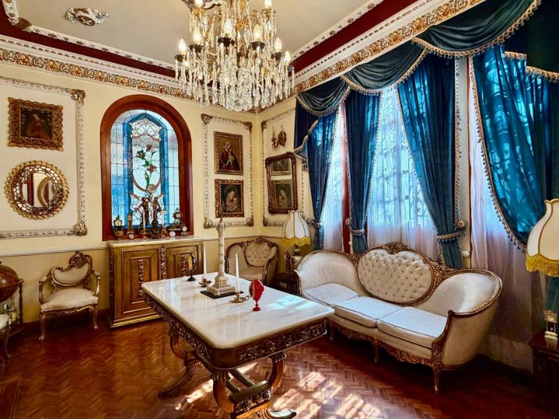 Salón ornamentado con una lámpara de araña de cristal y muebles antiguos en la Casa de las Campanas, un palacio de 1904 en Roma Norte, Ciudad de México
