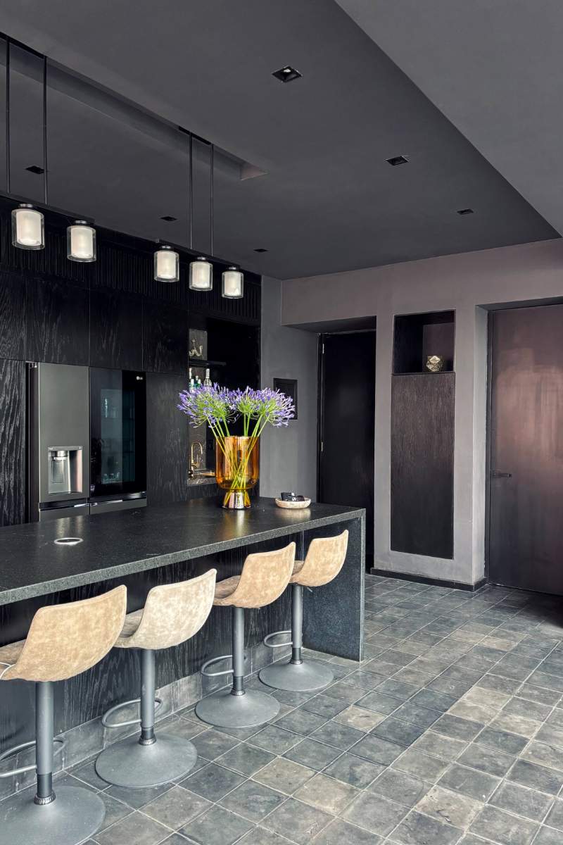 Cocina negra con barra desayunadora y luces colgantes en Lavish in Black, un departamento de 2 pisos en Condesa, Ciudad de México
