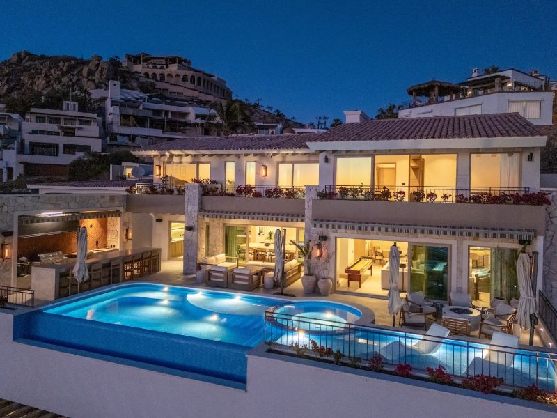 Casa La Maraca y su piscina infinita iluminadas al atardecer en Pedregal, Cabo San Lucas
