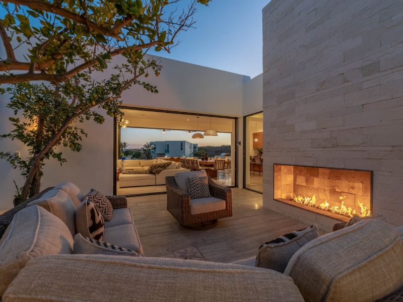 Salón al aire libre con chimenea al atardecer en Casa La Chula en Pedregal, Cabo San Lucas