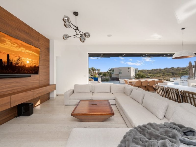 Sala de estar con una pared de vidrio que da a la terraza de Casa La Chula en Pedregal, Cabo San Lucas