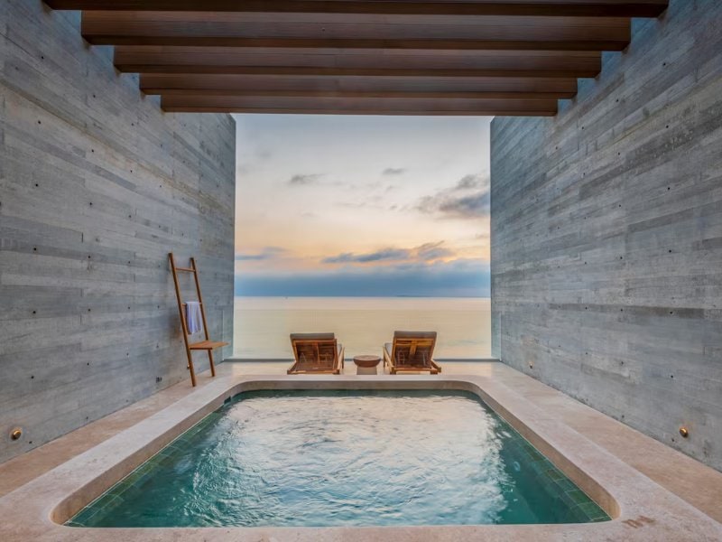 Piscina profunda con paredes de concreto que enmarca una vista al mar al atardecer en Casa Karina, una villa frente al mar en Punta Mita