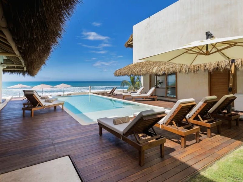 Terraza de la piscina con tumbonas frente al mar en Villa Chukum, una villa frente al mar en Punta Mita en la playa de Litibú