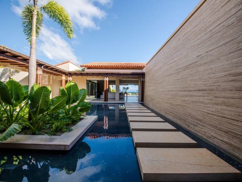 Pasarela de piedra sobre un espejo de agua en Casa Agua, una villa de Lagos del Mar en Punta Mita