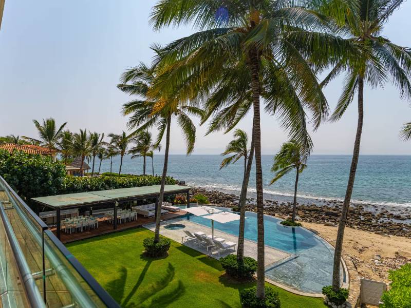 Césped, palmeras y piscina sobre la costa rocosa en la villa Breeze 5-18 en Punta Mita