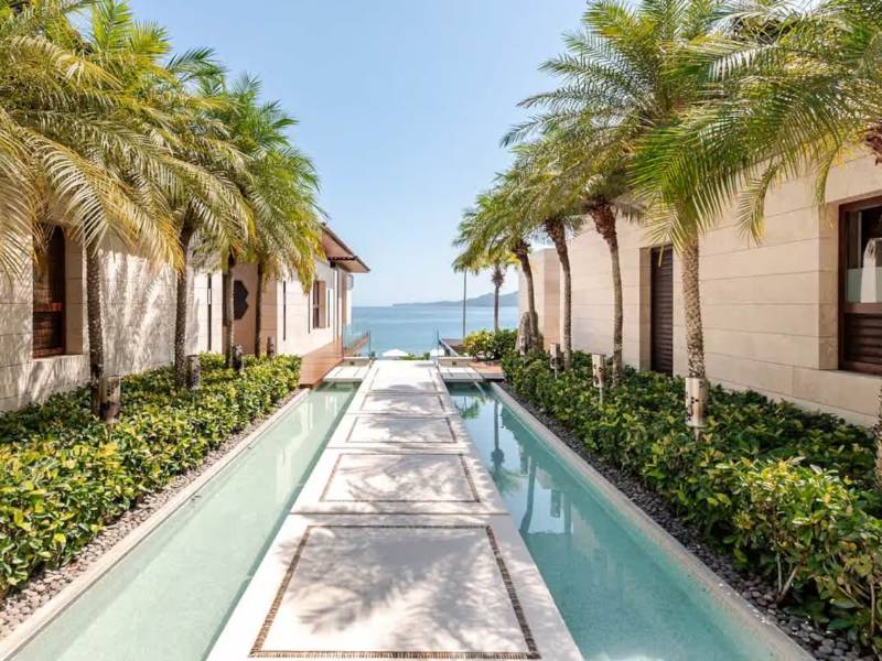 Canal de agua bordeado de palmeras que conduce hacia el océano en Casa Colmena, una villa de Kupuri frente a la playa en Punta Mita